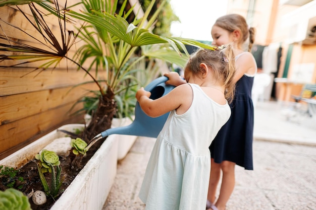 Dos hermanas con lata regando las flores en la terraza de la casa