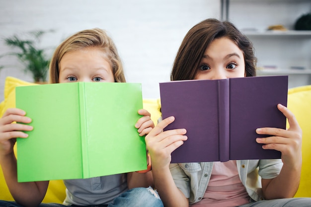 Dos hermanas leyendo libros y cubriéndose la cara