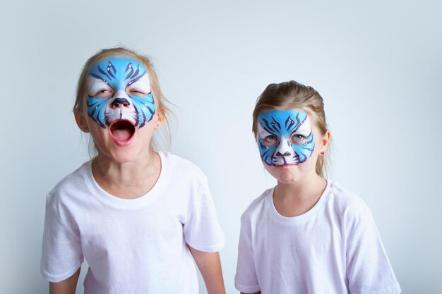 Foto dos hermanas con maquillaje acuático en forma de un tigre del zodiaco de agua azul