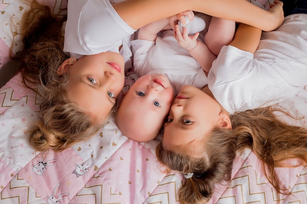 dos hermanas mayores sostienen a un bebé en sus brazos