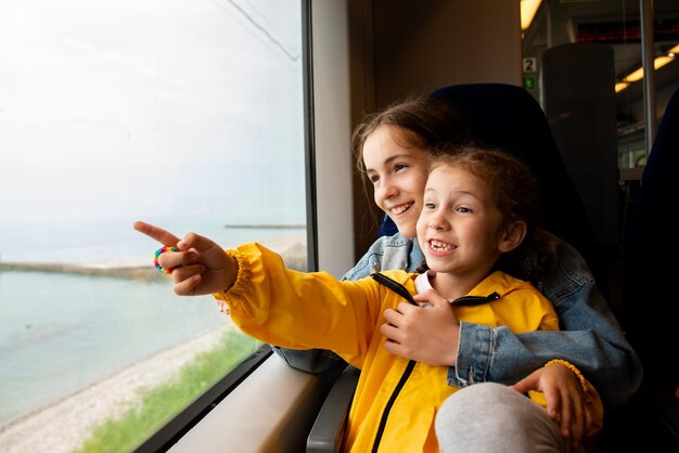 Dos hermanas miran por la ventana de un tren al mar. Las chicas hablan y se divierten. Viaje. Reflexión. Vacaciones. El verano. Vacaciones familiares.