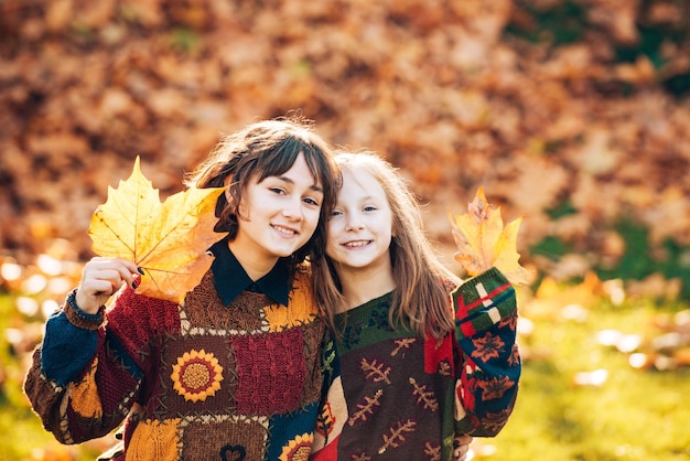 Dos hermanas niñas con hojas de naranja otoñales Belleza de mujer sana y natural Niña sonriente con