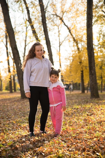 Dos hermanas de pie en el parque de otoño abrazándose