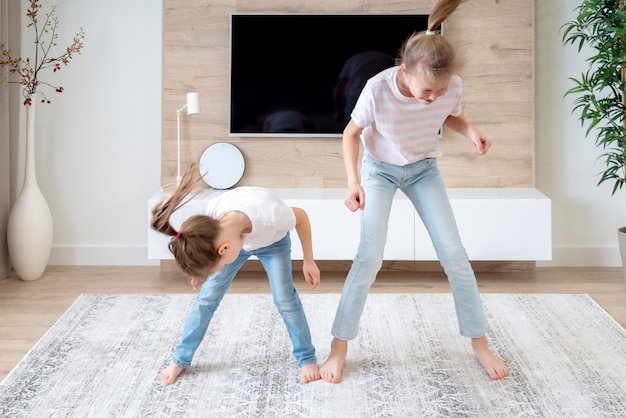 Dos hermanas que se divierten bailando en la sala de estar, concepto de familia feliz