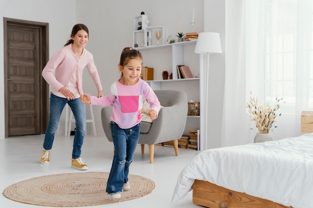 Foto dos hermanas sonrientes jugando en casa