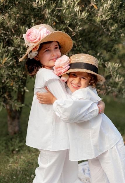 Dos hermanas sonrientes con sombreros y flores abrazándose con amor