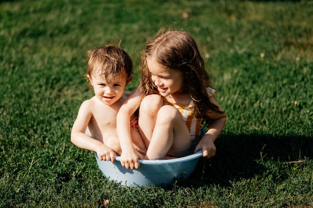 Dos hermanas se subieron a un recipiente con agua fría en un día caluroso y se zambulleron en el agua en el patio de una casa en el pueblo.