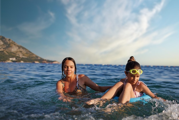 Dos hermanas en trajes de baño juegan con un anillo inflable en el mar