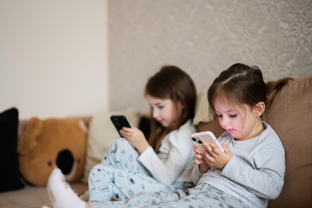 Dos hermanas usan pijamas jugando teléfonos temprano en la mañana
