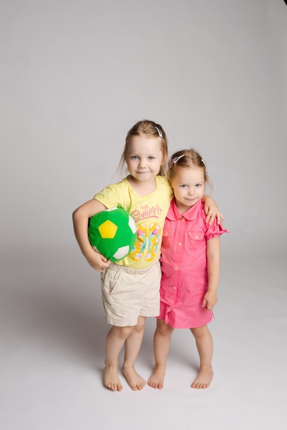 Dos hermanitas posando mientras juegan con pelota