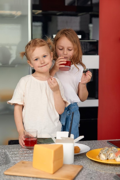 Dos hermanitos divirtiéndose y comiendo en la cocina de casa con comida japonesa