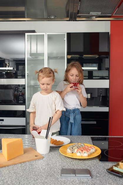 Dos hermanitos divirtiéndose y comiendo en la cocina de casa con comida japonesa