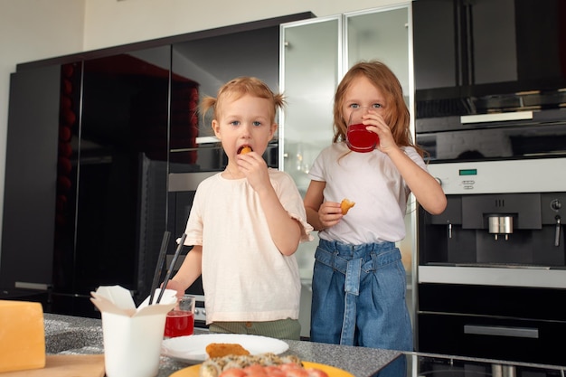 Dos hermanitos divirtiéndose y comiendo en la cocina de casa con comida japonesa