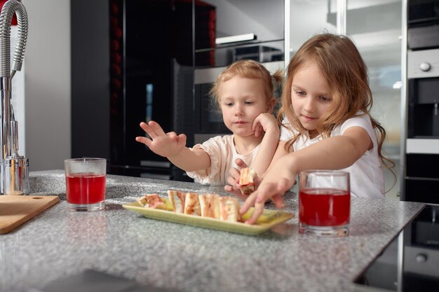 Dos hermanitos divirtiéndose y comiendo en la cocina de casa con comida japonesa