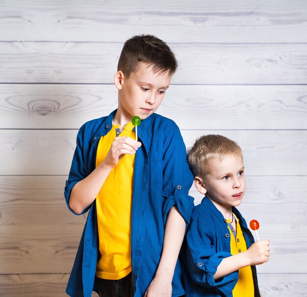 Dos hermanos con camisetas amarillas y camisas azules con paletas de colores