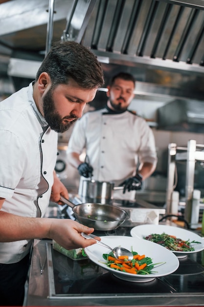 Dos hermanos están haciendo ensalada Chef profesional preparando comida en la cocina