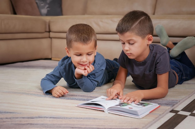 dos hermanos están tirados en el suelo leyendo un libro