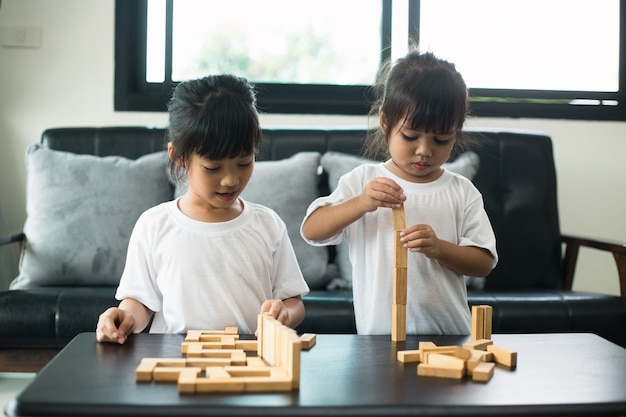 Dos hermanos felices jugando un juego con bloques de madera en casa con alegría