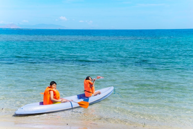 Dos hermanos haciendo kayak en la playa