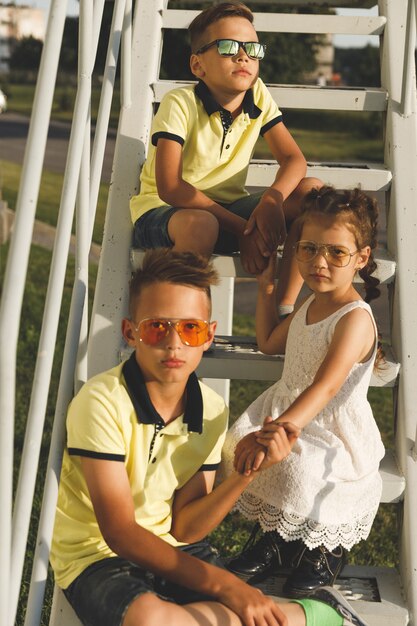 Dos hermanos y una hermana están sentados en las escaleras.