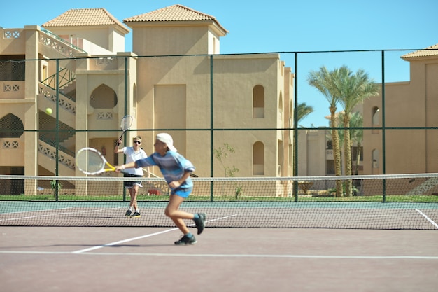 Dos hermanos jugando en la cancha de tenis al aire libre