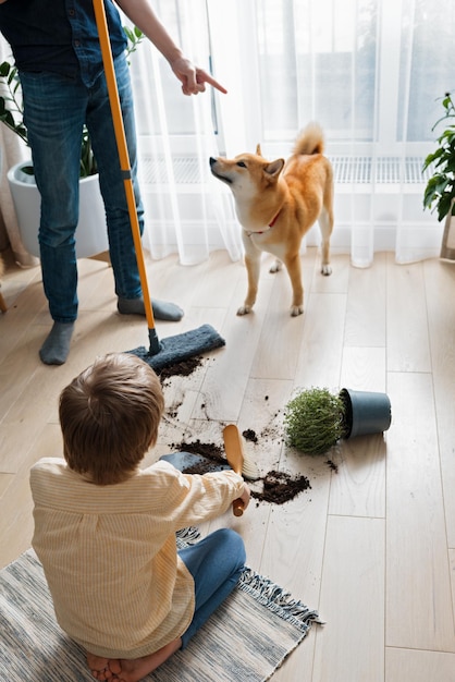 Foto dos hermanos limpiando el lío que su perro culpable doméstico hizo concepto de daño a mascotas