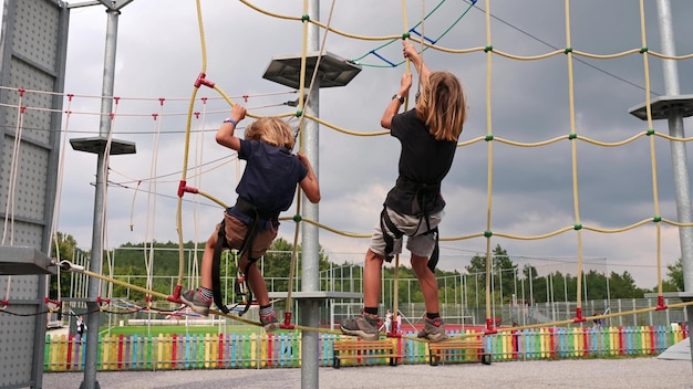 Dos hermanos sortean audazmente obstáculos en un parque de cuerdas fortaleciendo su vínculo y espíritu de aventura. Verano