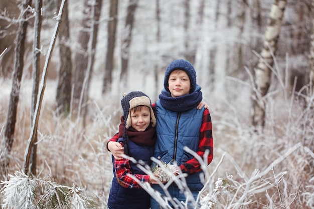 Dos hermanos en walr en bosque de invierno. Mejores amigos jugando juntos.