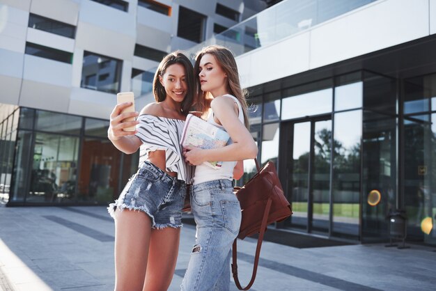 Dos hermosa joven estudiante feliz con mochila cerca del campus de la universidad y hacen una foto selfie. Concepto de educación y ocio