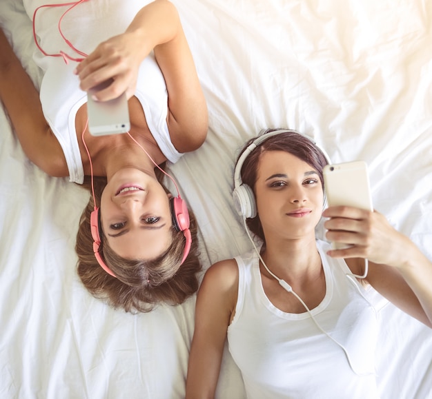 Dos hermosas chicas en auriculares escuchando música.