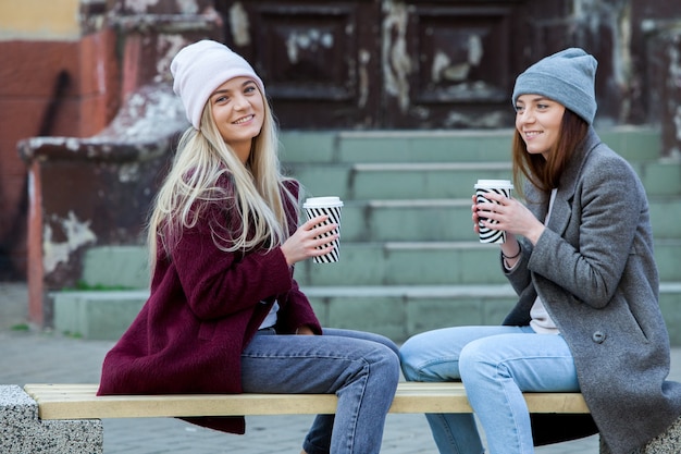 dos hermosas chicas de cabello largo tomando café en la ciudad