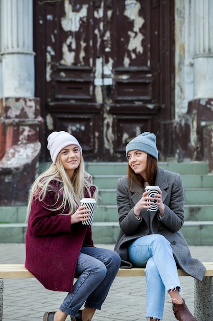 dos hermosas chicas de cabello largo tomando café en la ciudad