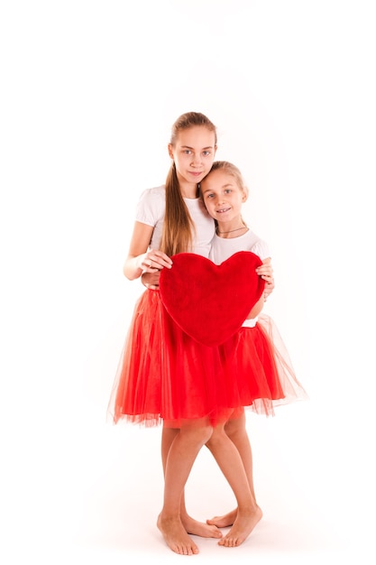 Dos hermosas chicas con corazón rojo aislado. concepto de San Valentín, amor y felicidad.