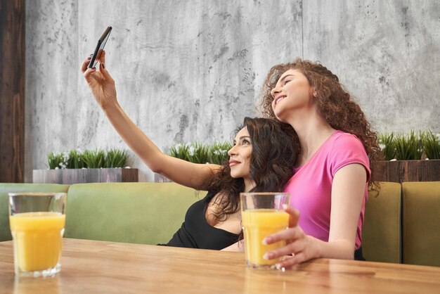 Dos hermosas chicas haciendo selfie en café.