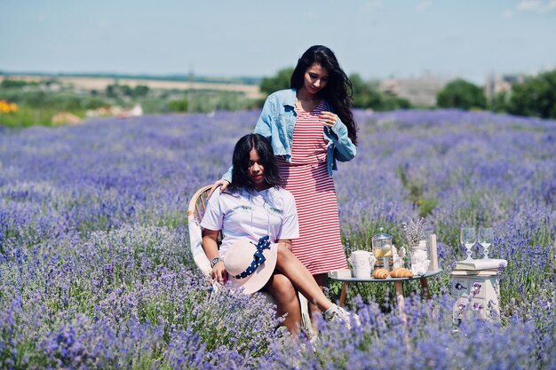 Dos hermosas chicas indias sentadas en un campo de lavanda púrpura con decoración