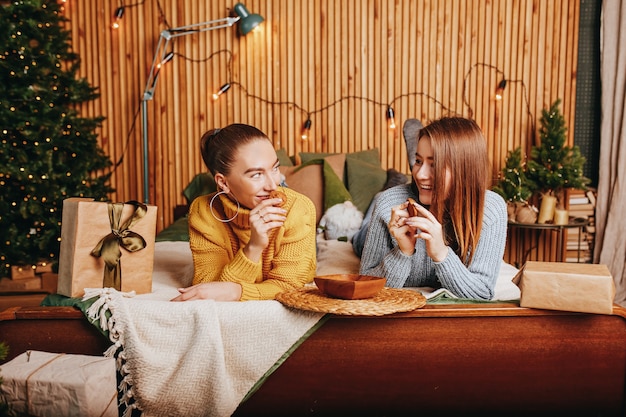 Dos hermosas chicas jóvenes felices alegres novia dan regalos de Navidad