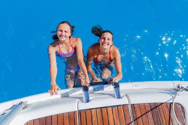 Dos hermosas chicas jóvenes relajándose en yate en Grecia