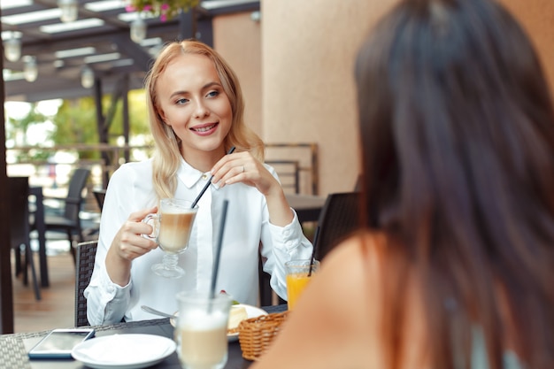 Dos hermosas chicas jóvenes sentadas junto a la mesa en el café