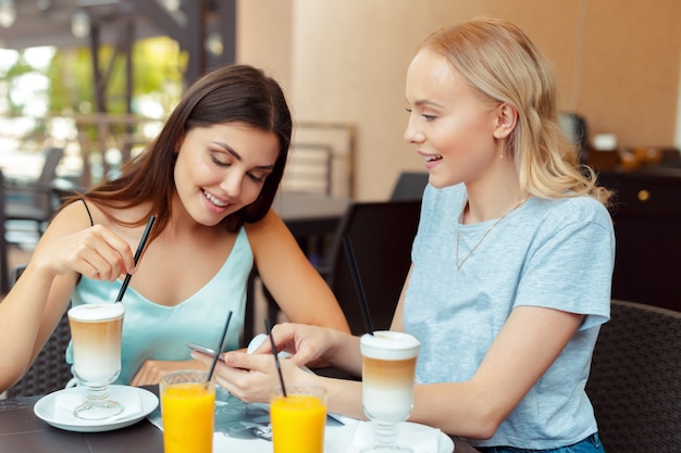 Dos hermosas chicas jóvenes sentados a la mesa en el café