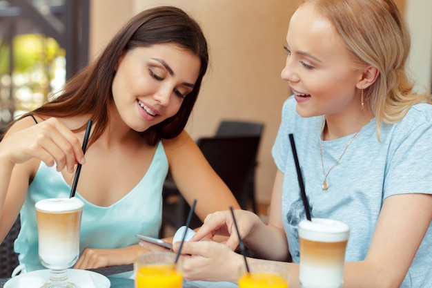 Dos hermosas chicas jóvenes sentados a la mesa en el café