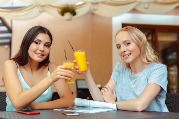 Dos hermosas chicas jóvenes sentados a la mesa en la cafetería