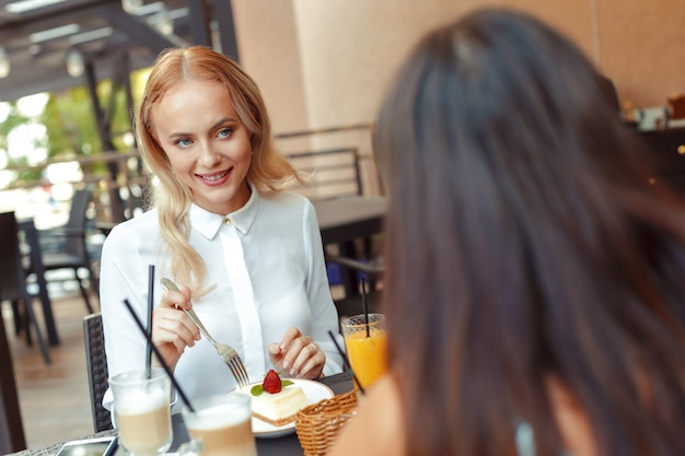 Dos hermosas chicas jóvenes sentados a la mesa en la cafetería