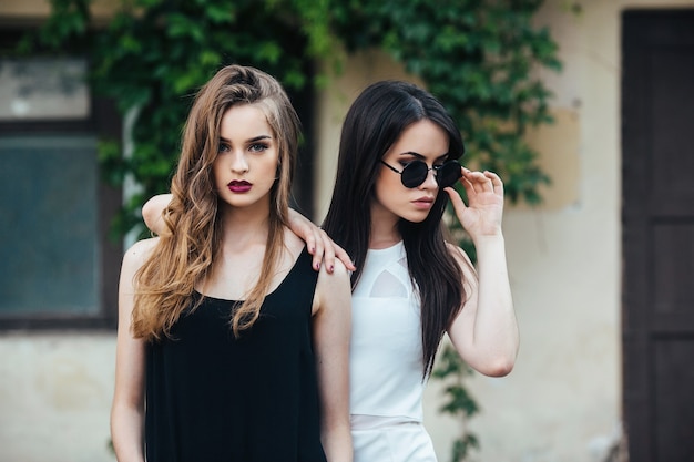 Dos hermosas chicas jóvenes en vestidos posando delante de casa