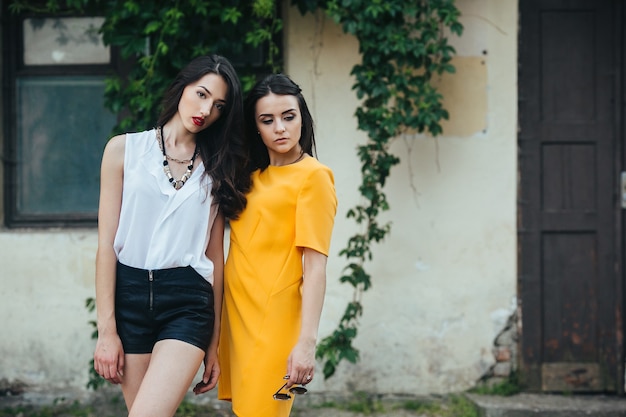 Dos hermosas chicas jóvenes en vestidos posando delante de casa