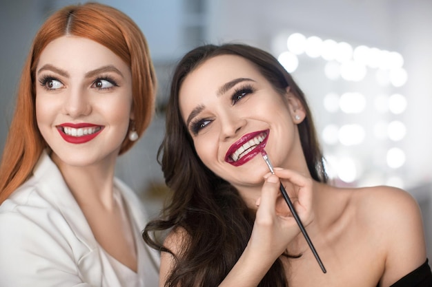 Dos hermosas chicas sonriendo y usando lápiz labial