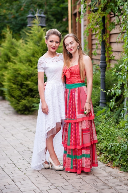 Dos hermosas chicas en vestidos blancos y rojos.