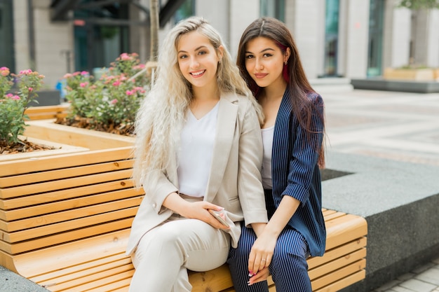 Dos hermosas hembras jóvenes en trajes de verano en un banco