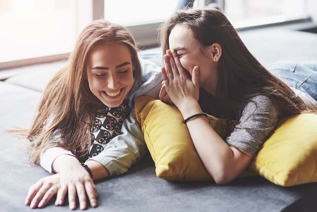 Dos hermosas hermanas gemelas jóvenes pasar tiempo junto con almohadas. Hermanos divirtiéndose en casa concepto