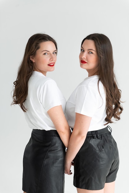 Dos hermosas hermanas gemelas posando en un fondo blanco