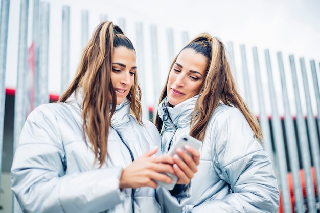 Dos hermosas hermanas gemelas con smartphone